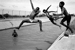 Первый день школьных каникул, 33 градуса по Цельсию. Дети из городка Бриджтон купаются в оросительном канале у скотобойни. Южная Африка, 8 декабря 2003